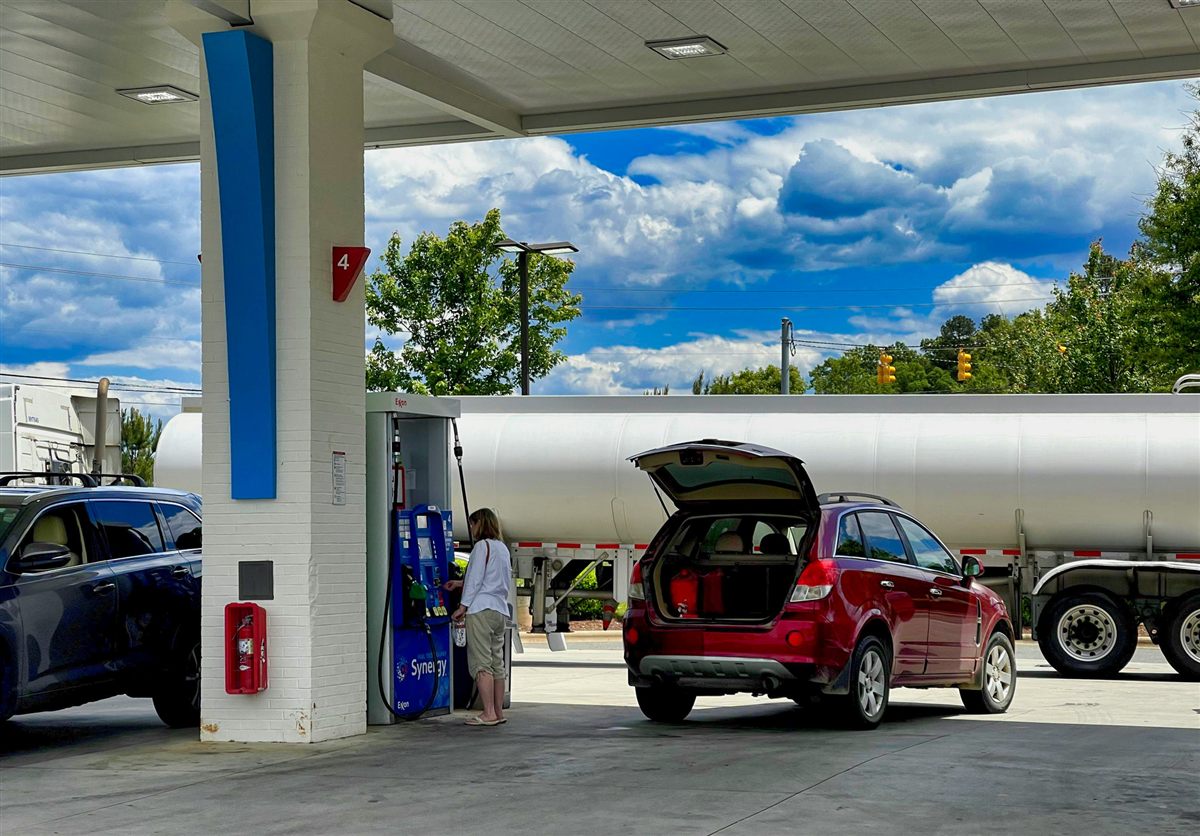 Gas station with a vehicle refueling and a tanker truck in the background